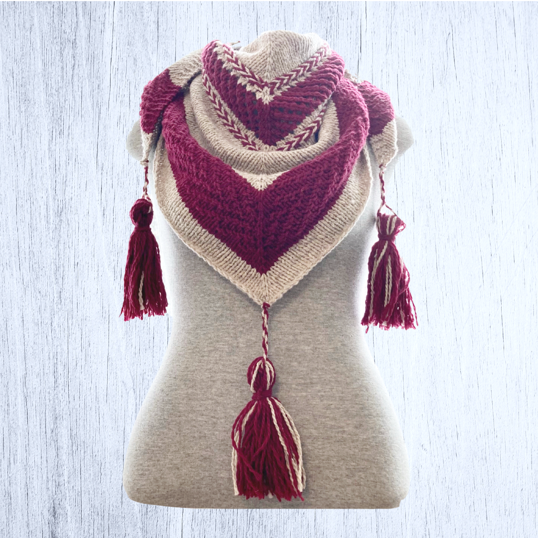 An oversized beige and red shawl with three tassels is draped around a gray mannequin torso