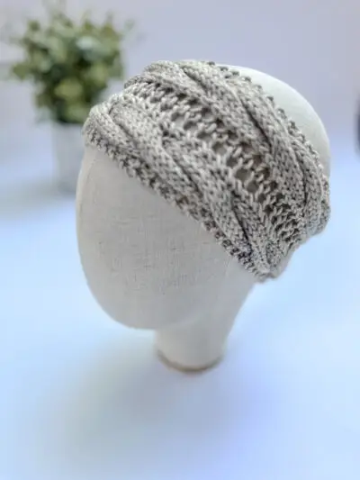 A light gray, hand-dyed merino ear warmer headband is displayed on a cloth mannequin head.