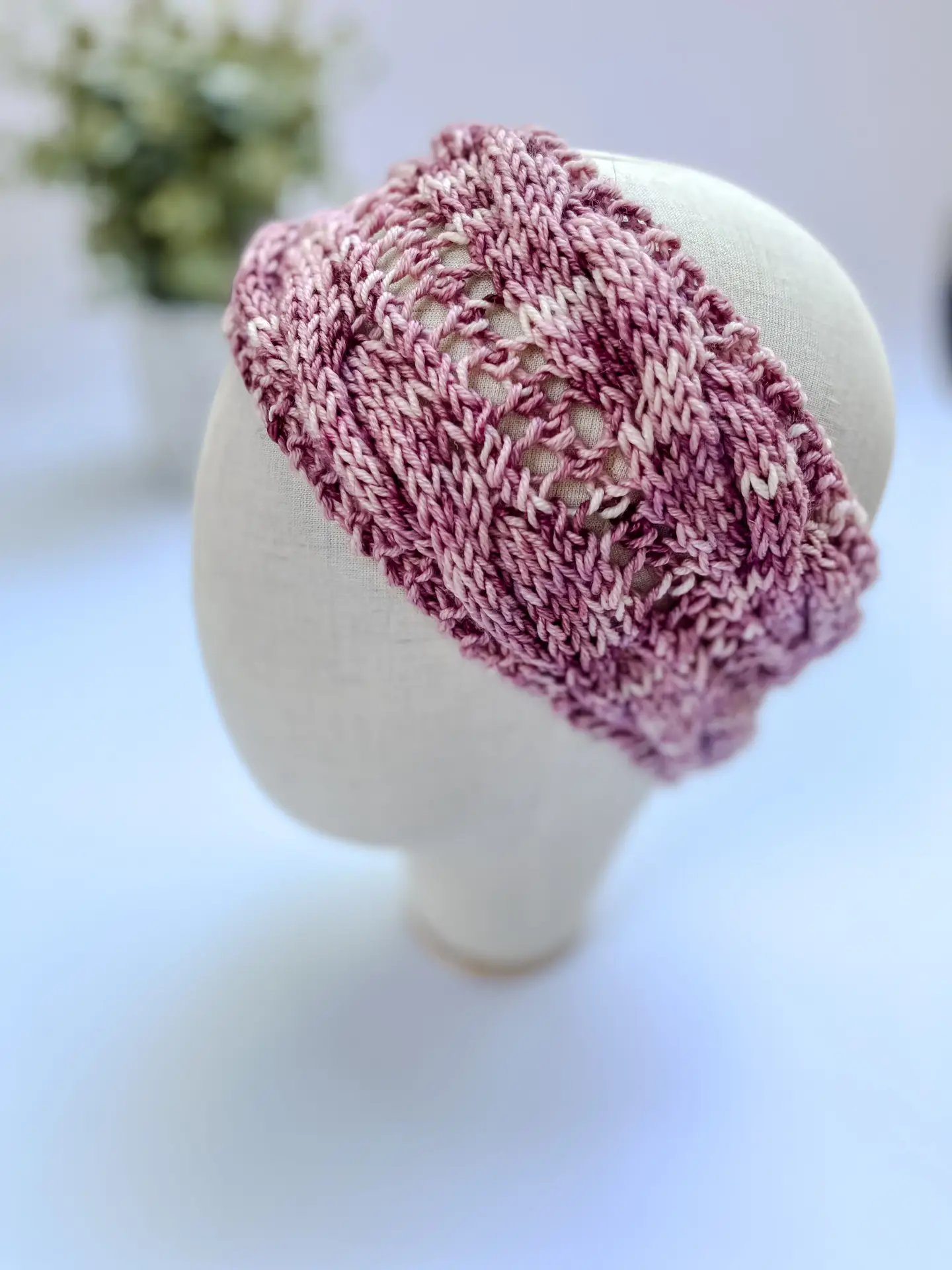 A pink, red & white, hand-dyed merino ear warmer headband is displayed on a cloth mannequin head.