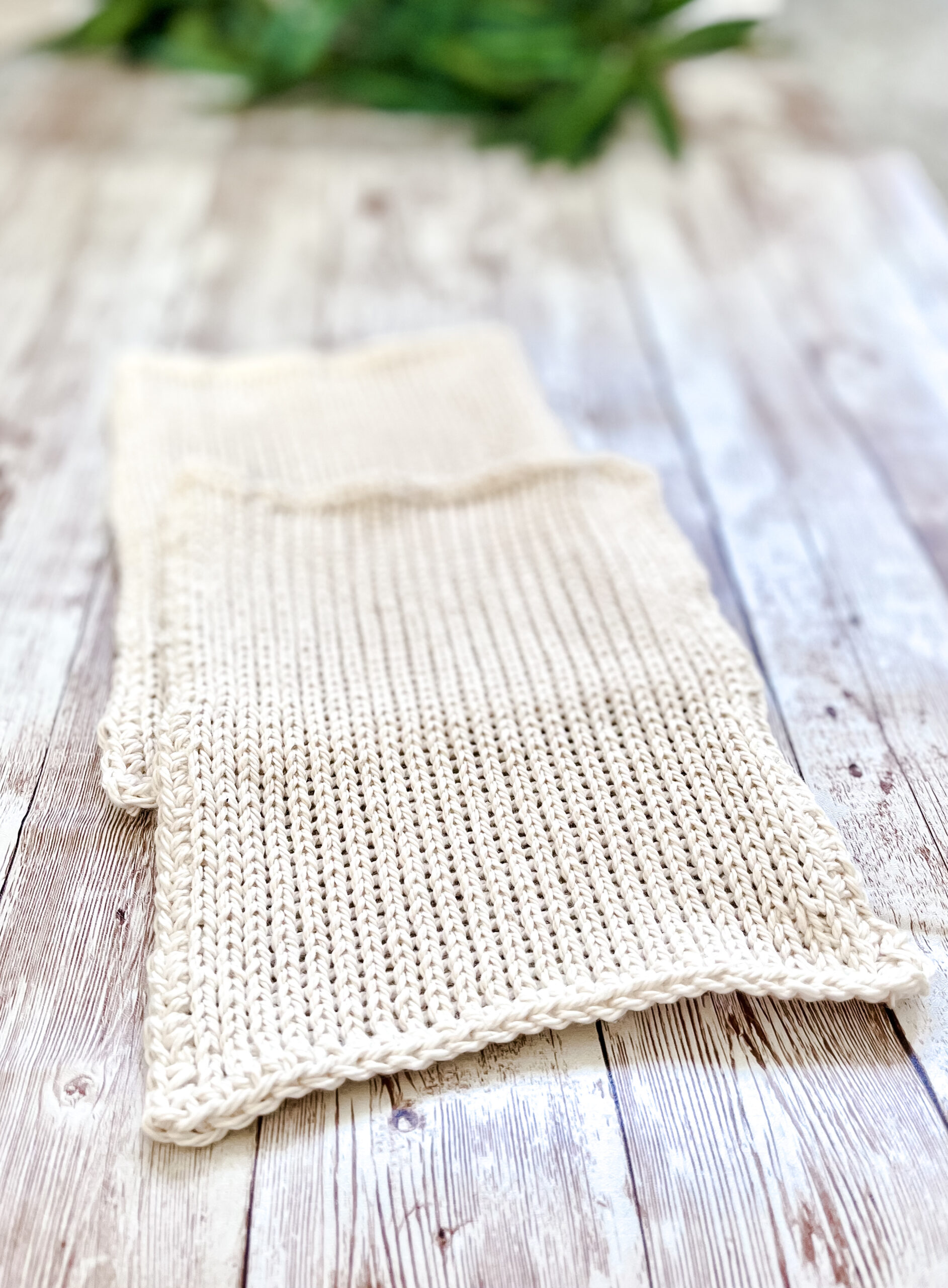 A pair of white Virginia-grown cotton washcloths rests on a wood plank