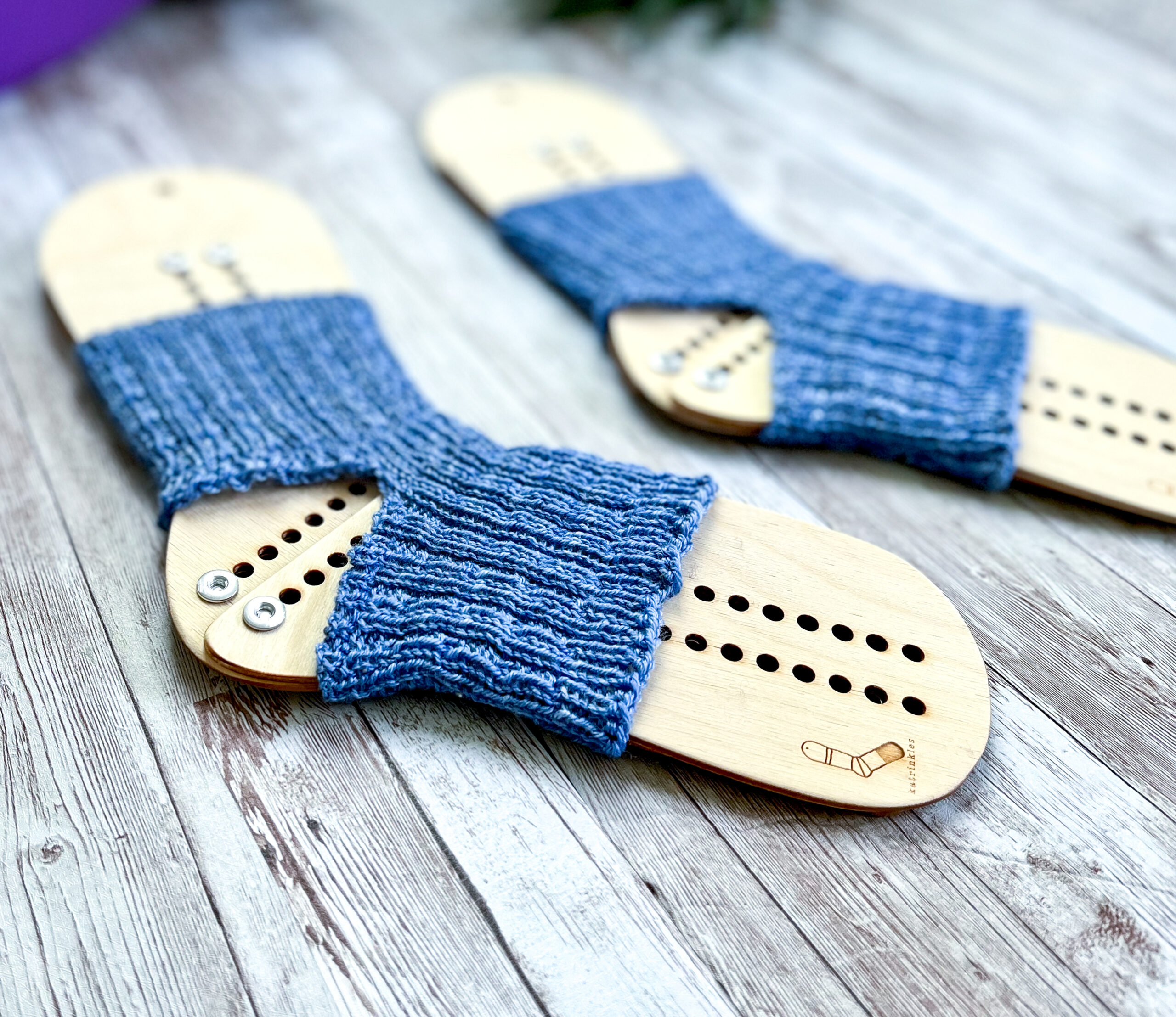 A pair blue yoga socks on wooden sock blockers are on a wood panel
