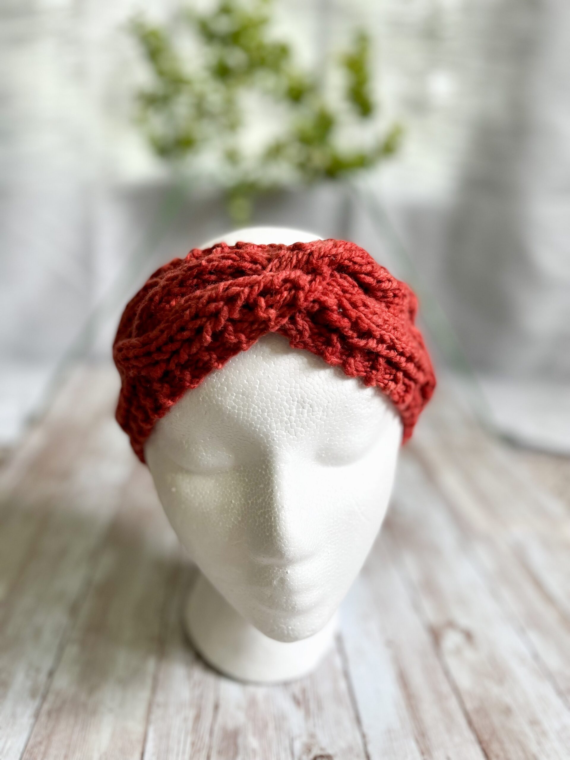 A mannequin head displays an orange hand-dyed, Virginia-raised merino cabled ear warmer