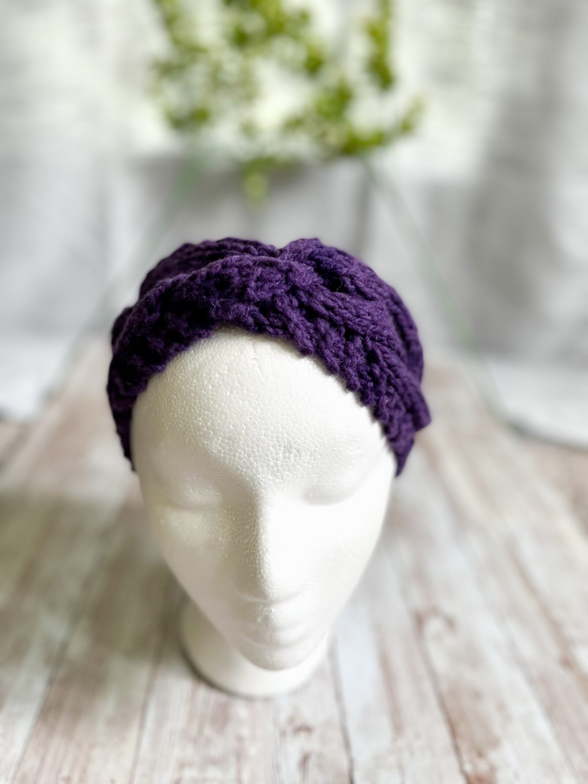 A mannequin head displays a purple hand-dyed, Virginia-raised merino cabled ear warmer