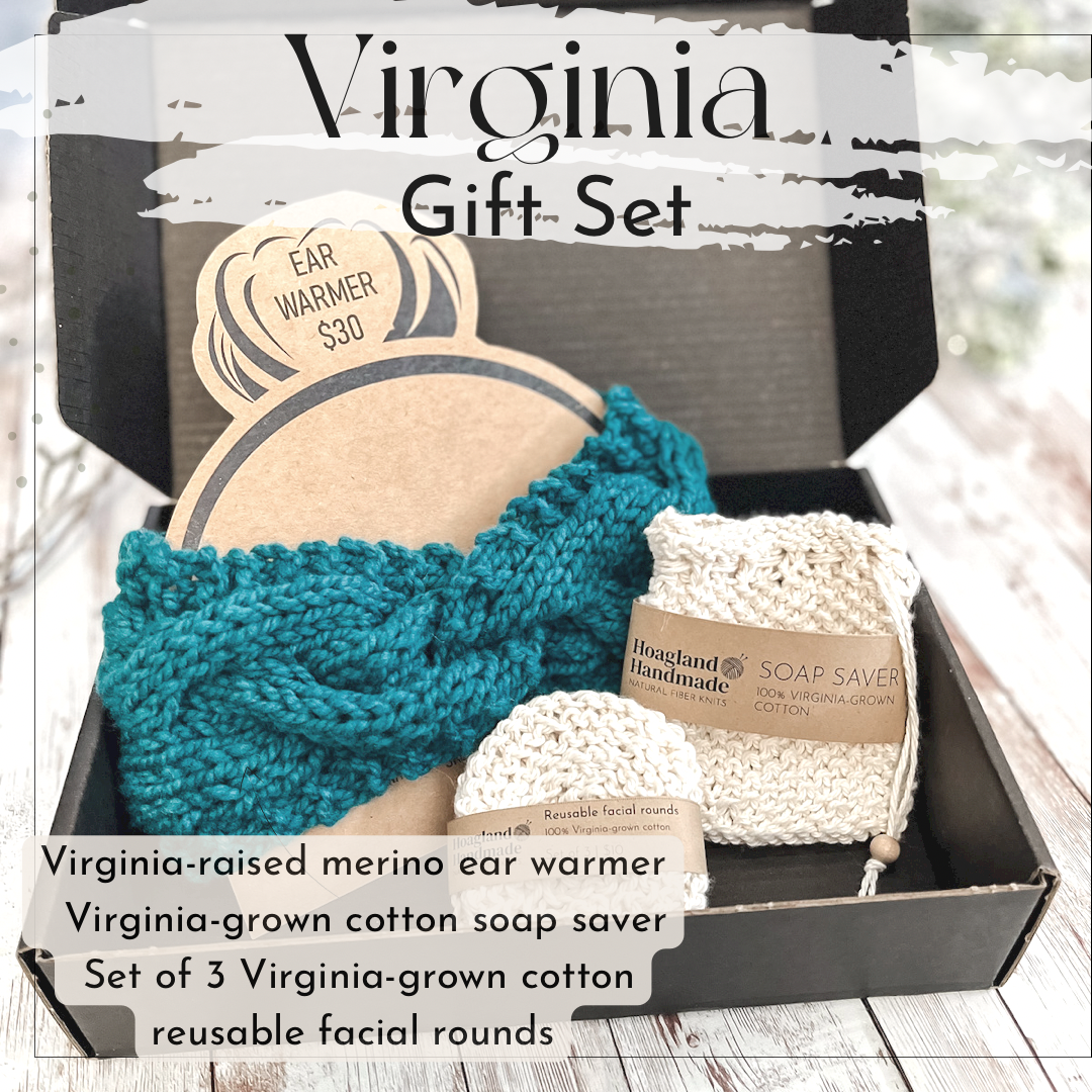A black box contains a teal hand-dyed merino ear warmer displayed on a Kraft paper head with a messy bun, a Virginia-grown cotton soap saver and set of reusable facial rounds. The box sits on a wood panel. The text on the image reads "Virginia gift set" and includes a list of the items included in the Virginia gift set