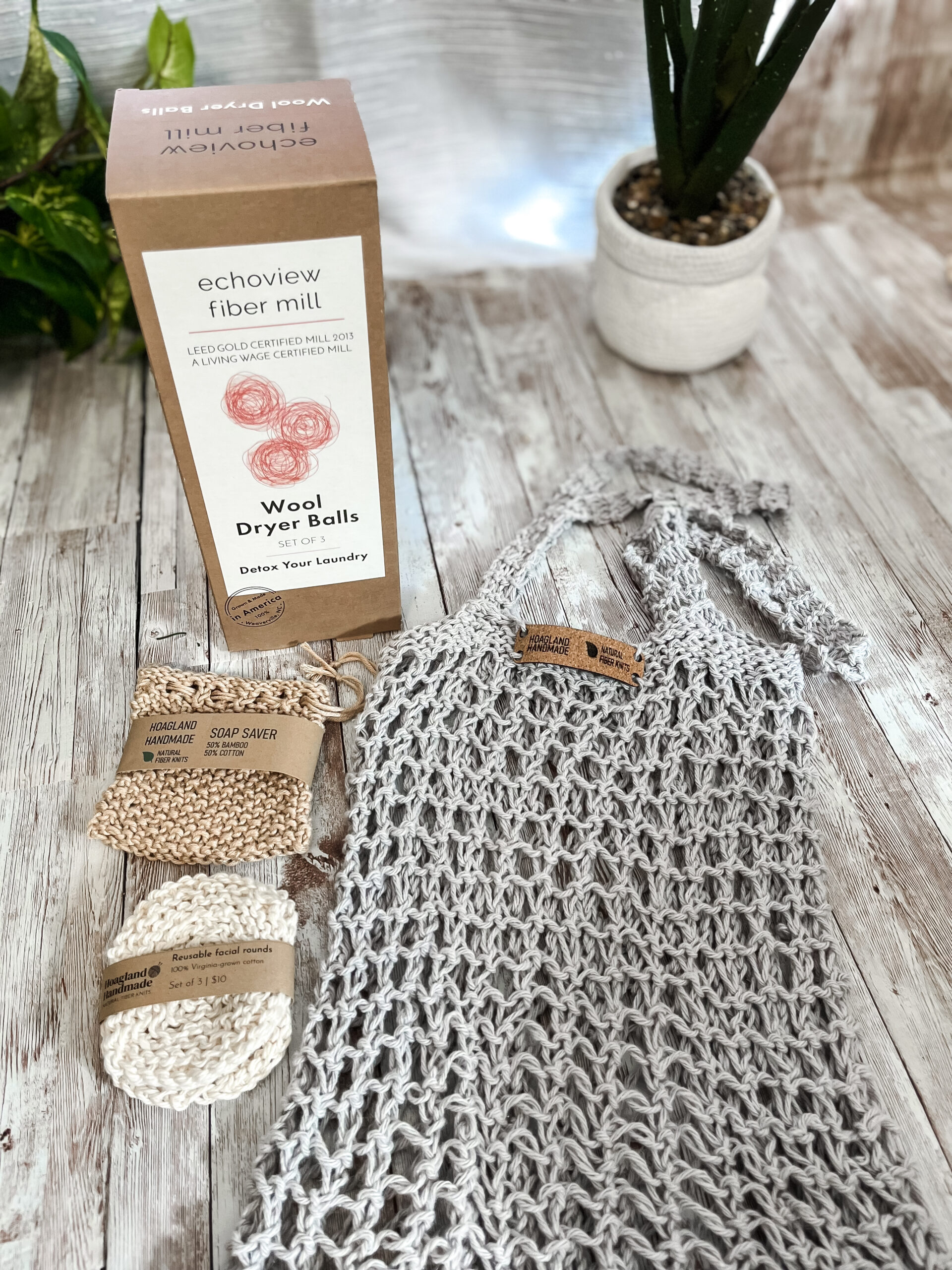 The Zero Waste gift set is pictured showing a box of 3 US Wool dryer balls, a tan bamboo/cotton soap saver pouch wrapped in a kraft paper label from Hoagland Handmade, a set of 3 usable facial rounds knit from Virginia-grown cotton and wrapped in a a kraft paper label from Hoagland Handmade, and a gray recycled cotton knit market tote