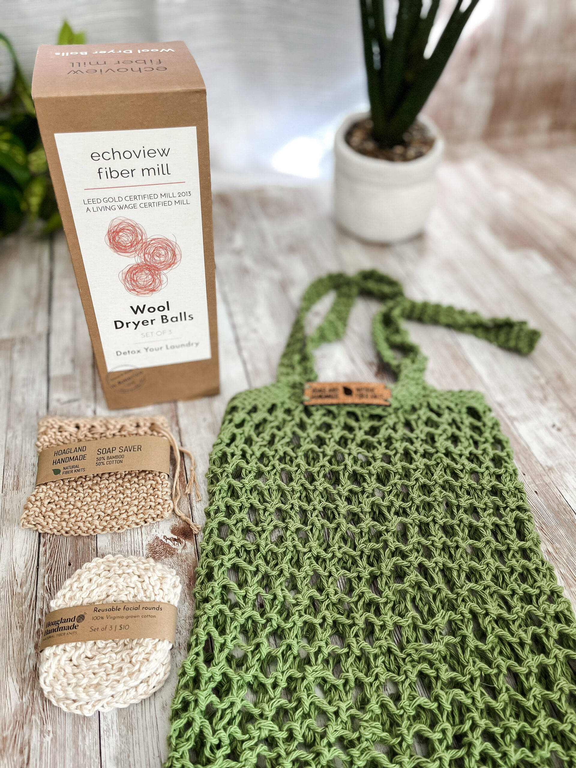 The Zero Waste gift set is pictured showing a box of 3 US Wool dryer balls, a tan bamboo/cotton soap saver pouch wrapped in a kraft paper label from Hoagland Handmade, a set of 3 usable facial rounds knit from Virginia-grown cotton and wrapped in a a kraft paper label from Hoagland Handmade, and a green recycled cotton knit market tote